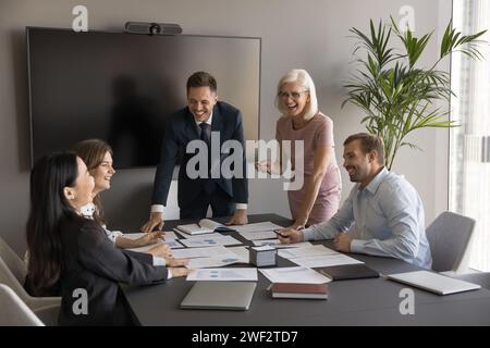 Simpatici professionisti aziendali che esaminano i report cartacei sul tavolo da riunione Foto Stock