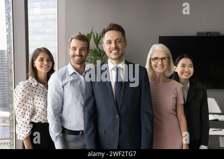 Colleghi felici di diverse età che stanno dietro un giovane leader maschile Foto Stock