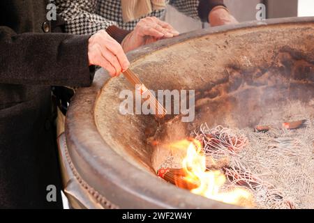 Tokyo, Giappone. 28 gennaio 2024. Un uomo brucia un bastone d'incenso al tempio Takahata Fudoson di Hino City, sobborghi occidentali di Tokyo. I visitatori si riuniscono per comprare le bambole Daruma (senza pupille dipinte sugli occhi), in cerca di fortuna durante l'anno. Le persone colorano in un allievo quando si fa un desiderio, o si stabilisce un obiettivo, e quando il desiderio si avvera, o l'obiettivo viene raggiunto, riempiono l'altro allievo. Alla fine dell'anno, le bambole Daruma usate vengono restituite al tempio per essere bruciate. Crediti: ZUMA Press, Inc./Alamy Live News Foto Stock