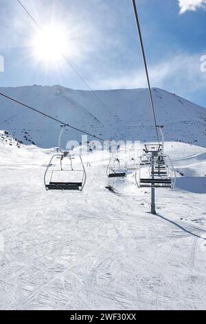 Skilift con sedie vuote presso la stazione sciistica invernale. Giornata di sole, cielo blu. Pista di montagna innevata. Costruzione della funivia. Attività invernale per le vacanze. Chunkurchak, Bishkek, Kirghizistan Foto Stock