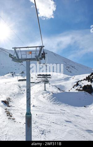 Skilift con sedie vuote presso la stazione sciistica invernale. Giornata di sole, cielo blu. Pendio montano. Costruzione della funivia. Attività invernale per le vacanze. Chunkurchak, Bishkek, Kirghizistan Foto Stock