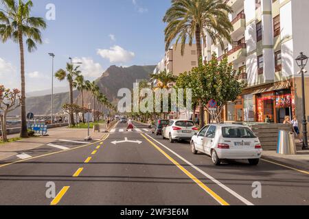 Persone che attraversano il viale marittimo principale fiancheggiato da palme o la strada costiera sull'isola delle Canarie di la Palma. Foto Stock