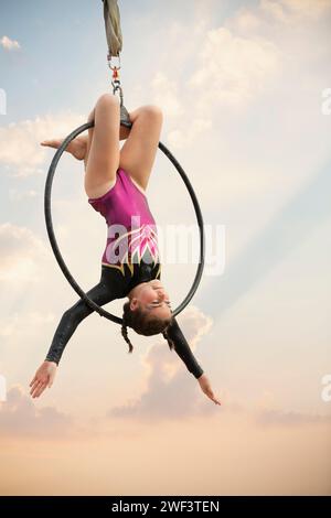 ginnasta di 12 anni che si esibisce all'aria aperta su un canestro aereo Foto Stock
