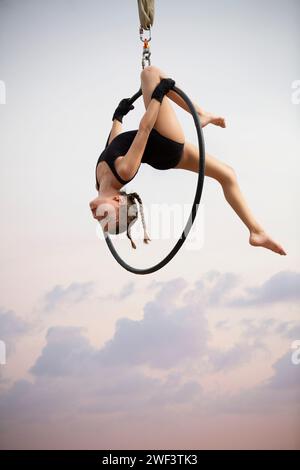 ginnasta di 12 anni che si esibisce all'aria aperta su un canestro aereo Foto Stock