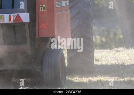 Falciare i prati di fiori selvatici in autunno a Hawthorn Hive, contea di Durham. Primo piano delle ruote di un trattore e di una macchina per la rilegatura che sollevano la polvere Foto Stock