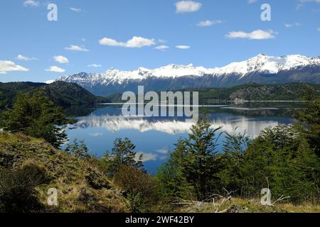 Le montagne innevate del Cile della Patagonia si riflettono nelle acque tranquille del Lago Cisnes vicino a Villa o'Higgins sulla Carretera Austral. Foto Stock