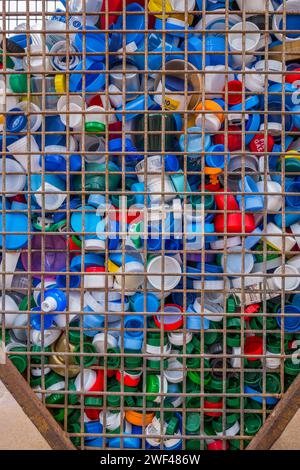 Ampia selezione di bottiglie di plastica colorata in una zona a gabbia a forma di cuore. Foto Stock