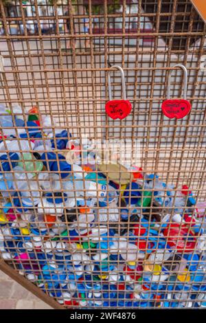 Ampia selezione di bottiglie di plastica colorata in una zona a gabbia a forma di cuore. Foto Stock