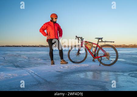 Ciclista maschile anziano con la sua bici in ghiaia su un lago ghiacciato in Colorado - Boyd Lake State Park Foto Stock