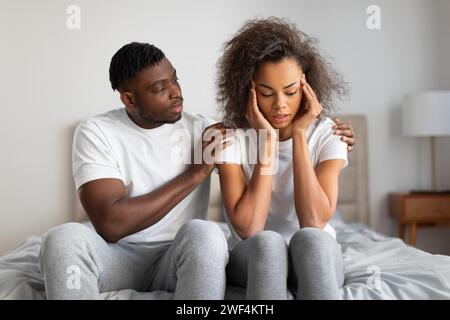 Marito nero Millennial di supporto che conforta e sostiene la moglie depressa al chiuso Foto Stock