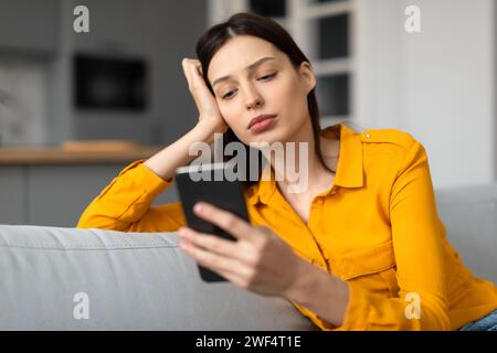 Giovane donna stressata con il telefono che sembra turbata Foto Stock