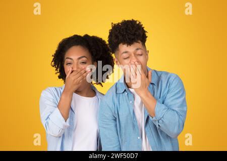 Scioccata giovane donna afroamericana e uomo con le mani sopra un occhio Foto Stock