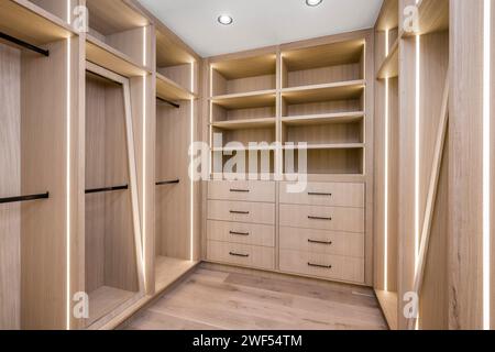 Spazioso armadio a muro con eleganti ripiani in legno, cassetti e scaffali aperti per l'organizzazione Foto Stock