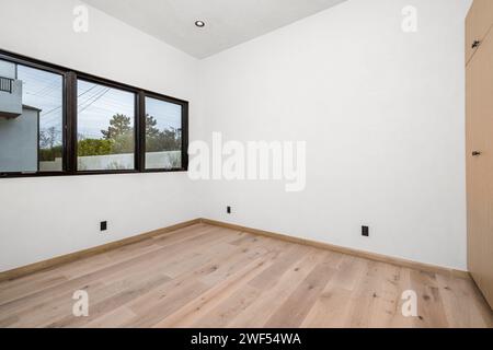Camera bianca vuota con pavimenti in legno e finestra Foto Stock