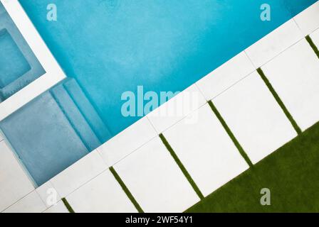 Una tranquilla piscina immersa in una lussureggiante erba verde adiacente a una bella casa Foto Stock