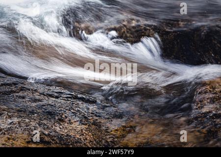 Lunga esposizione, astratta, acqua vorticosa che scorre sulle rocce, Foto Stock