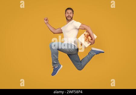 Corriere regalo a mezz'aria. Un ragazzo energico che corre veloce con la confezione regalo. Consegna di regali e regali Foto Stock