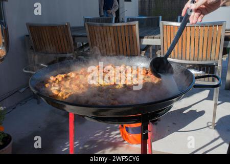 Preparare la paella nel cortile. Tradizionale pasto domenicale per famiglie spagnole. Foto Stock