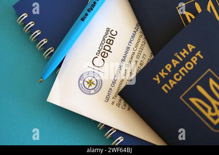 KIEV, UCRAINA - 27 NOVEMBRE 2023 logo del servizio passaporti con passaporto ucraino internazionale e penna sul tavolo Foto Stock