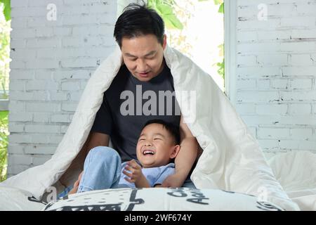 Padre e figlio felici che si stanno divertendo sul letto Foto Stock