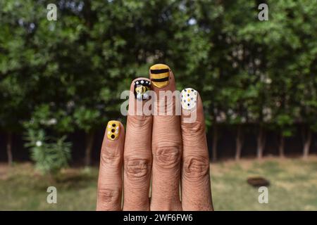 Creative Nail Art con tema Bee. Disegni per unghie, disegni per alveare con strisce, motivi a puntini sui colori giallo, bianco e nero Foto Stock