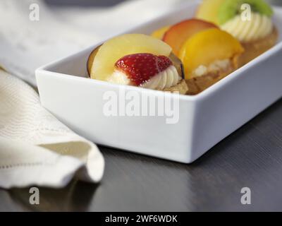 Una scatola di frutta assortita su un tavolo di legno Foto Stock