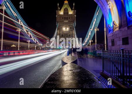 Londra. UK-01.27.2024. Una lunga esposizione notturna scattata sul Tower Bridge con un pedone, i turisti che visitano questo iconico monumento e i sentieri luminosi da Foto Stock