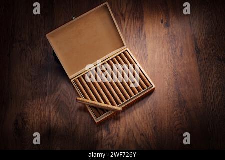 Vista dall'alto dei sigari in una scatola collocata su un pavimento di legno Foto Stock