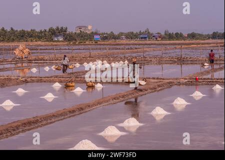 I lavoratori dei campi di sale trasportano cesti di rattan carichi con sale raccolto nei campi di sale. Fish Island, Kampot Province, Cambogia. Crediti: Kraig Lieb Foto Stock