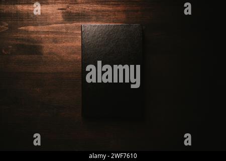 Mockup per notebook con copertina rigida in pelle nera su scrivania in legno, vista dall'alto Foto Stock