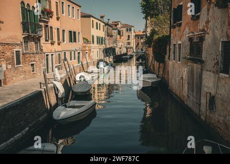 Le barche ormeggiate fiancheggiano un tranquillo canale residenziale circondato da tradizionali case veneziane in una giornata di sole. Foto Stock