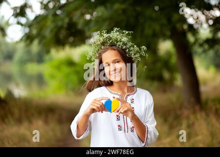 Ragazza ricamata e corona di fiori con cuore giallo e blu. Love Ukraine Concept. Indipendenza, bandiera, giorno della costituzione dell'Ucraina Foto Stock