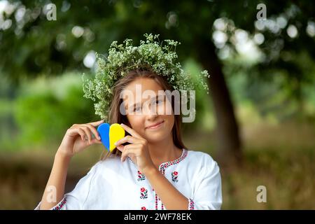 Ragazza ricamata e corona di fiori con cuore giallo e blu. Love Ukraine Concept. Indipendenza, bandiera, giorno della costituzione dell'Ucraina Foto Stock
