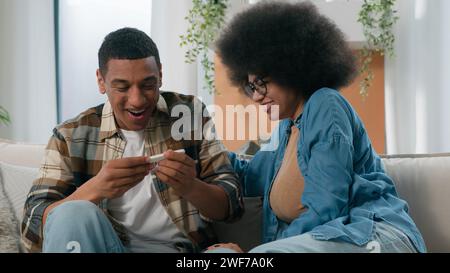 Coppia afro-americana marito e moglie felice fidanzata e fidanzato entusiasta con un test di gravidanza positivo rifornimento nella felicità della famiglia Foto Stock