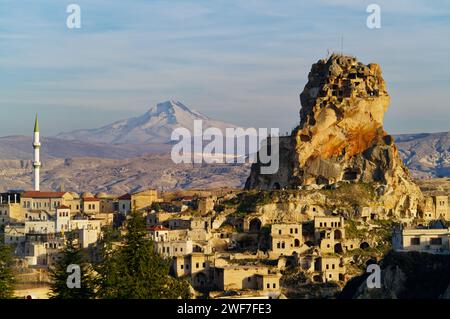 Vista del castello di Ortahisar tra le foglie rosse della Cappadocia, Turchia. Il Monte Erciyes innevato è visibile sullo sfondo Foto Stock