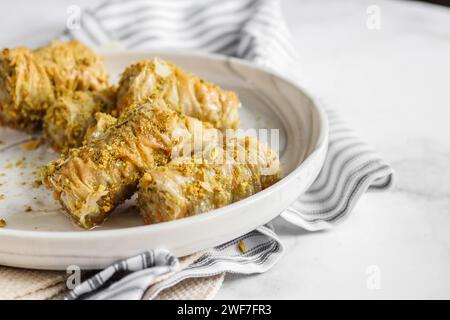 Primo piano del baklava arrotolato su un piatto bianco di marmo Foto Stock