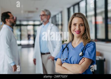 Ritratto di medico femminile in piedi nel corridoio dell'ospedale. Bella infermiera in uniforme, stetoscopio intorno al collo in una moderna clinica privata Foto Stock