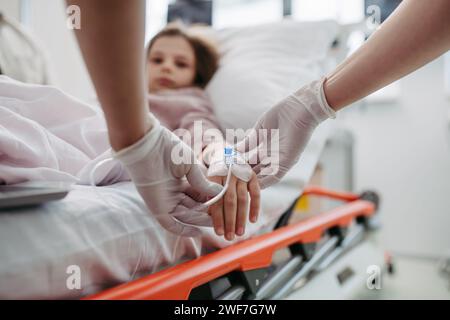 Primo piano dell'infermiera che inserisce la cannula IV nella mano di una bambina. IV, terapia endovenosa per pazienti pediatrici. Foto Stock