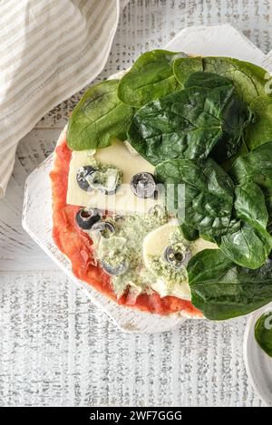 pizza con spinaci surgelati su uno sfondo di legno Foto Stock