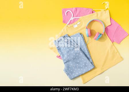 Un set di abiti alla moda per bambini. Jeans eleganti, T-shirt su sfondo giallo. Copia spazio Foto Stock