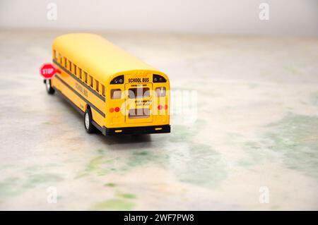 Scuolabus americano in miniatura di colore giallo standard con segnale di stop sul lato. Vista posteriore con messa a fuoco selettiva Foto Stock