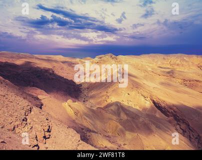 Deserto montuoso con cielo nuvoloso e colorato. Tramonto nel deserto Foto Stock