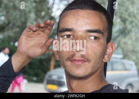 Primo piano faccia adulto ragazzo indiano con ritratto dietro, foto di ragazzo adolescente himalayano con ritratto dietro Foto Stock