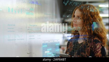 Immagine dei dati finanziari con icone sopra la donna d'affari caucasica in ufficio Foto Stock