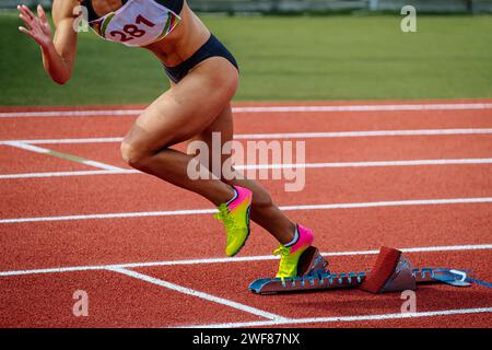 atleta femminile che corre da blocchi di partenza gara sprint, campionati estivi di atletica Foto Stock