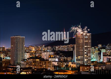 Una vivace esposizione di fuochi d'artificio che scoppia sul cielo notturno di Tbilisi, illuminando il paesaggio urbano con vari colori e motivi Foto Stock