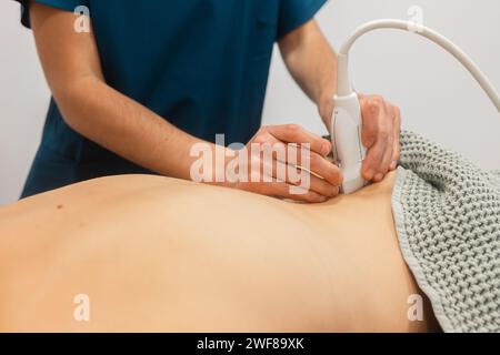 Un fisioterapista esegue la terapia a ultrasuoni sulla schiena del paziente, utilizzando un trasduttore sulla pelle Foto Stock