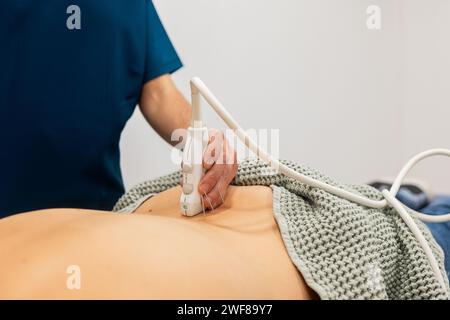 Un operatore sanitario esegue un'ecografia sull'area addominale del paziente, utilizzando un trasduttore per eseguire la scansione sulla pelle Foto Stock