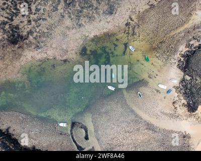 Vista dall'alto delle barche ormeggiate in una baia poco profonda con acque cristalline lungo la costa nord di Fuerteventura, vicino a Faro del Toston Foto Stock