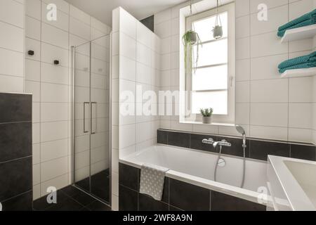 Un bagno elegante e contemporaneo caratterizzato da uno schema di colori bianco e nero con linee pulite e luce naturale. Foto Stock
